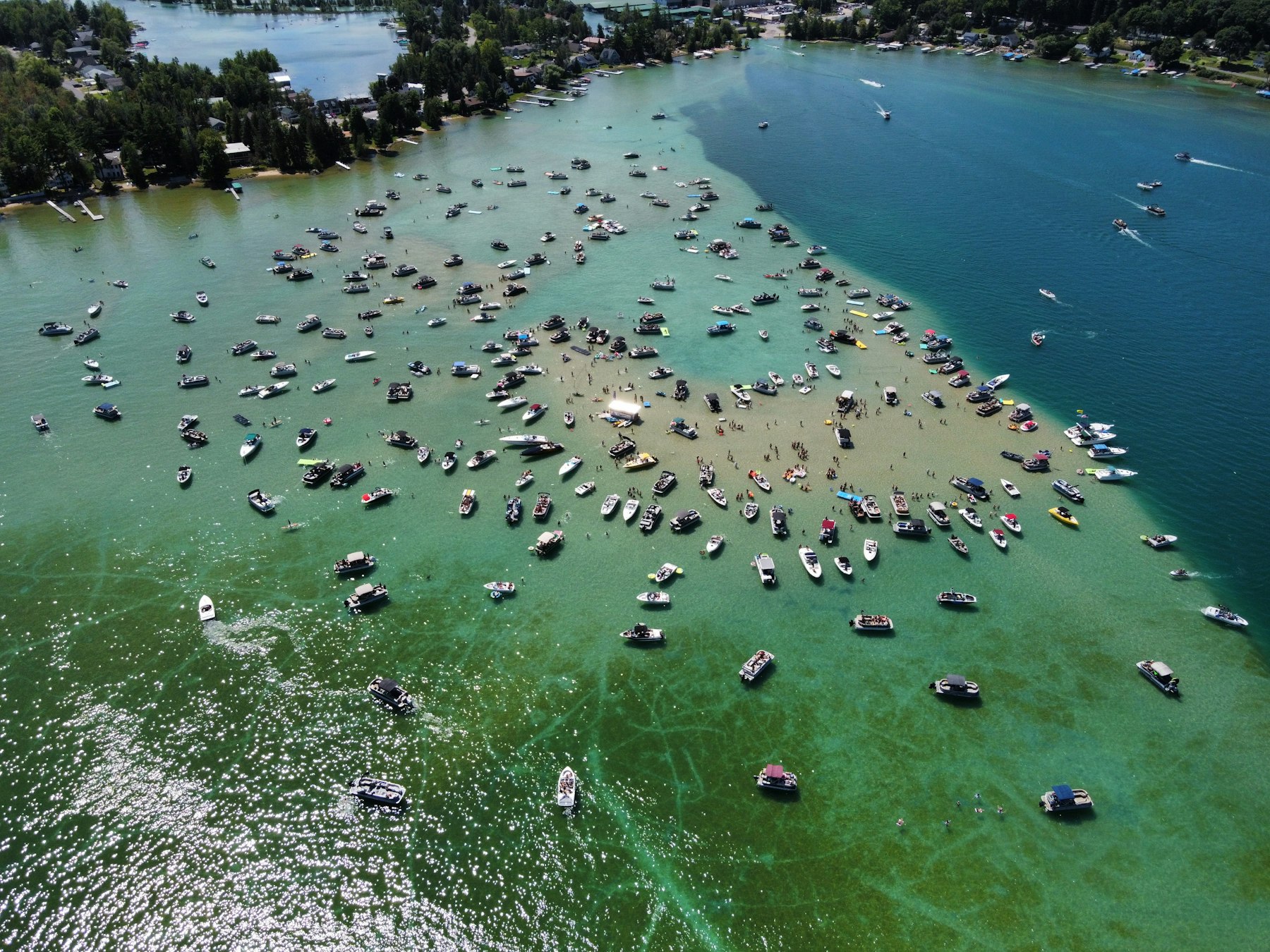 Dozens of modern boats gathered on a shallow sandbar with swimmers